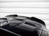 A glossy black car's hood with streamlined air vents sits stationary, reflecting light. It's positioned against a backdrop of horizontal, white, textured panels.