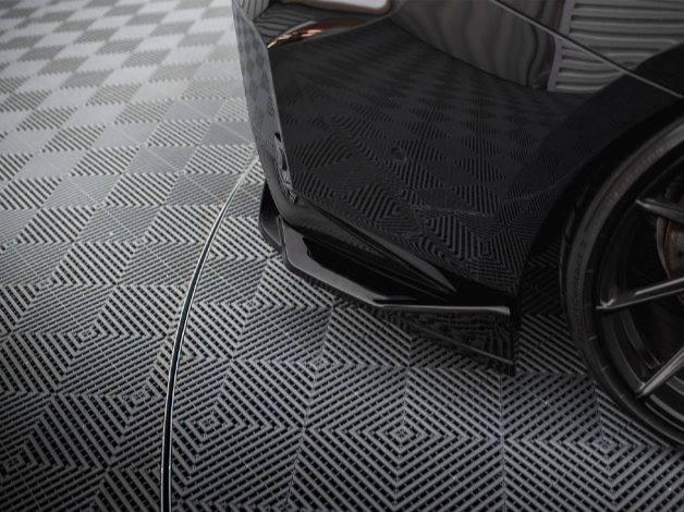 A sleek black car's rear bumper is parked on a patterned grid floor, surrounded by a symmetrical, geometric design in a well-lit, indoor setting.