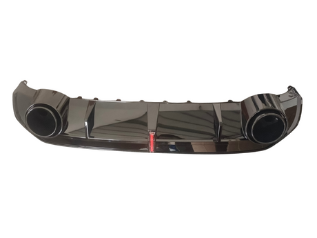 Shiny black car bumper features large circular exhaust openings on each side, with a red reflector in the center. It rests against a plain white background.
