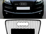 A black Audi car with a prominent front grille displays the brand's logo and a blank license plate space; below, a detached honeycomb-style Audi grille is shown against a plain background.