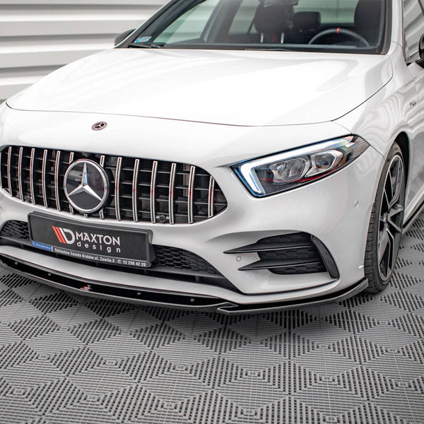 A white luxury car with a detailed front grille and distinctive headlights is parked in an indoor setting with patterned flooring. Logo text on plate reads: "MAXTON design."