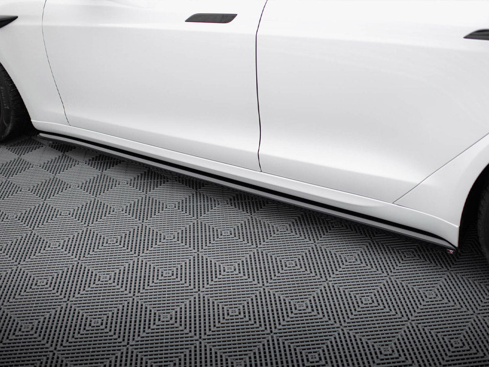 White car side, featuring sleek side skirts, parked on a patterned floor with geometric diamond shapes, creating a modern, polished appearance.