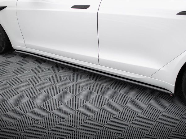 White car side, featuring sleek side skirts, parked on a patterned floor with geometric diamond shapes, creating a modern, polished appearance.