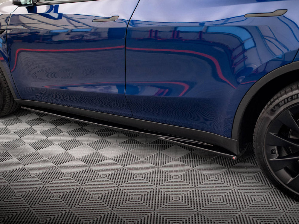 Car side profile reflecting surroundings, parked in a patterned garage. The vehicle is blue with black wheels, and the tire displays "MICHELIN" on it.