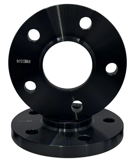 A polished, black metal wheel spacer with five holes, aligned vertically over another identical piece. Text reads "5x112 CB66.6" on both items. They rest on a plain, white background.