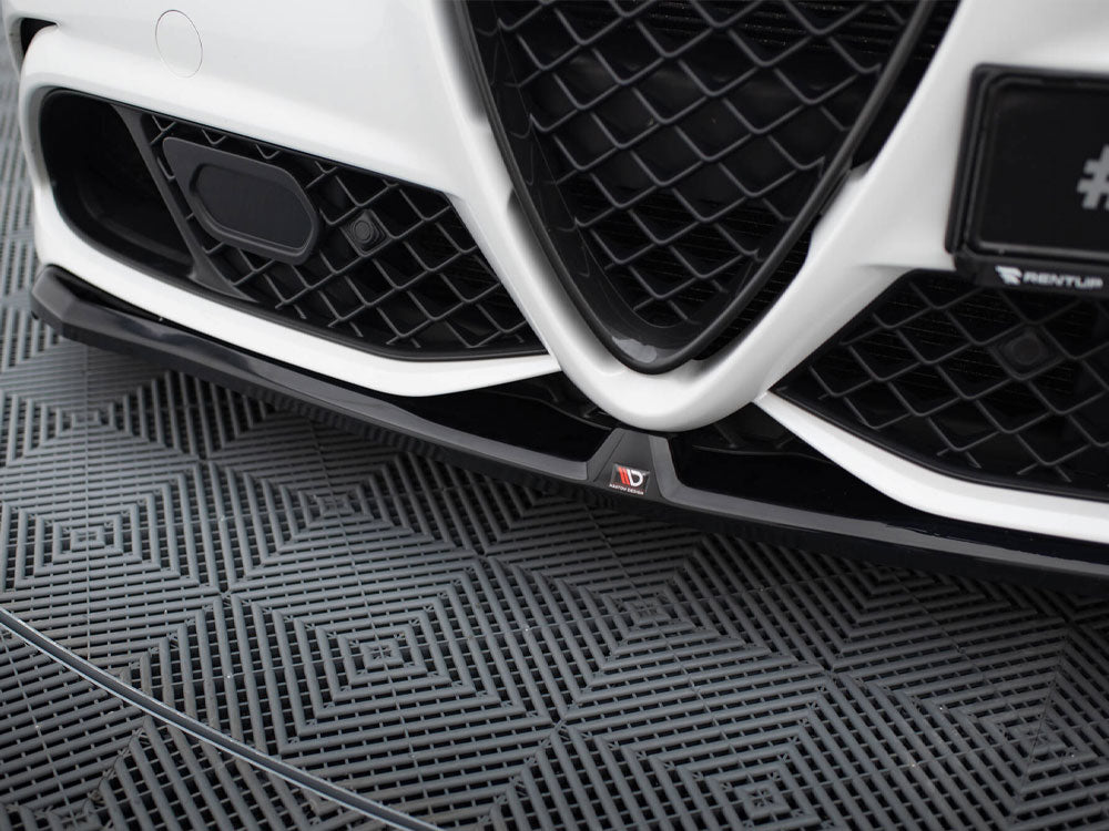 Car grille with a V-shaped design and black mesh pattern, positioned close to the ground. The left side shows a sensor. The floor has a textured geometric pattern.