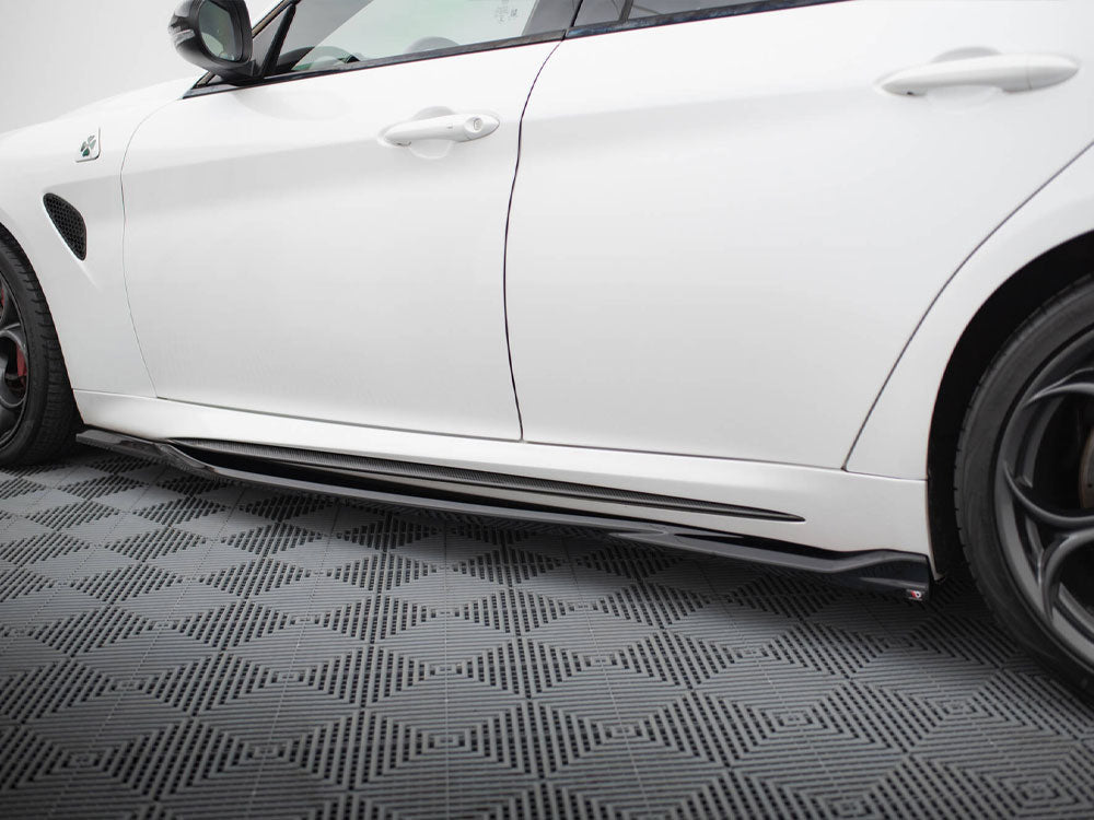 A white car is parked, showcasing its sleek side and black side skirt, on a patterned grey floor with geometric designs.