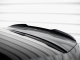 A glossy black car roof with a subtle spoiler reflects light, under a white striped ceiling, creating a sleek, modern appearance.
