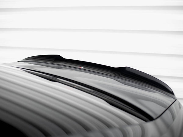 A glossy black car roof with a subtle spoiler reflects light, under a white striped ceiling, creating a sleek, modern appearance.