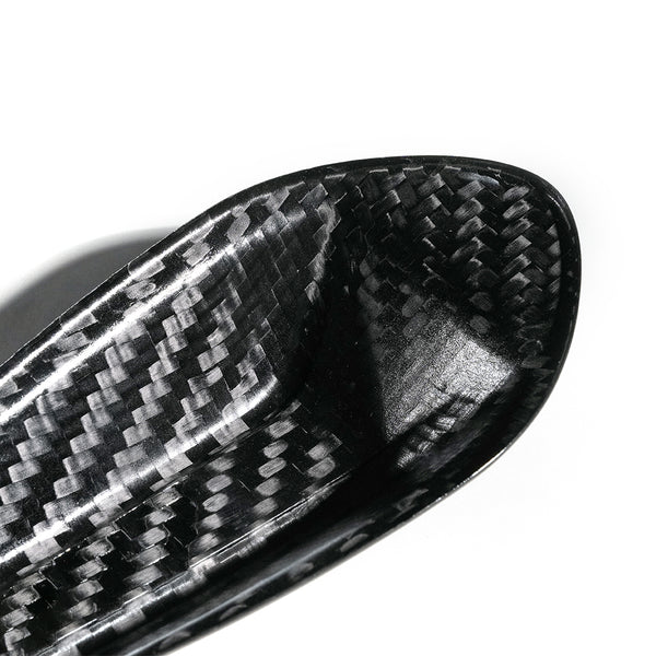 A close-up of a carbon fiber object, possibly a part of sports equipment, displaying a woven pattern. It is set against a plain white background.