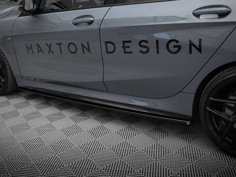 Car side displaying the text "MAXTON DESIGN" on its door, parked on a diamond-patterned floor. The vehicle is grey with black wheels, shown in a garage setting.