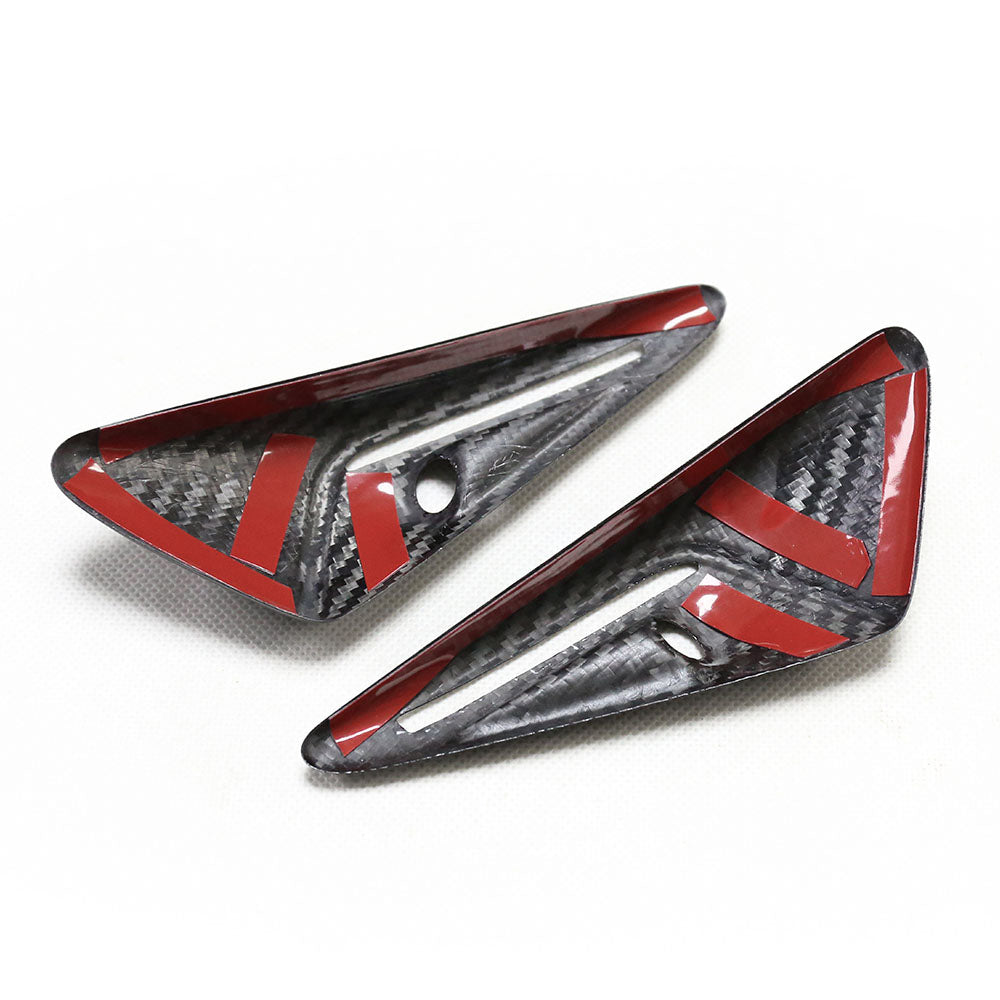 Two carbon fiber car parts with red accents and holes, positioned on a white surface. Each piece is triangular with a glossy finish, showing a textured pattern.