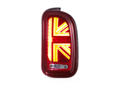 A red car taillight shaped like a Union Jack is illuminated brightly, positioned against a plain white background.