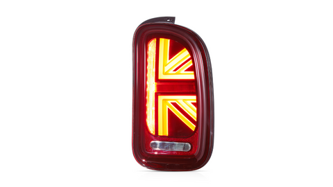 A red car taillight shaped like a Union Jack is illuminated brightly, positioned against a plain white background.
