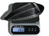A carbon fiber car part rests on a digital scale, displaying a weight of 26.5 grams. Surrounding text includes 