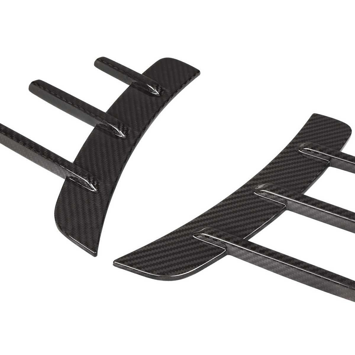Two curved carbon fiber car diffusers with vertical fins, lying against a white background.