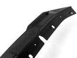 A contoured carbon fiber car part with multiple holes lies against a white background, showcasing a sleek, textured design often used for aerodynamic enhancements.