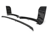Carbon fiber car aerodynamic parts, including a splitter and winglets, rest on a white background. These components feature sleek, glossy surfaces with a textured, woven pattern.