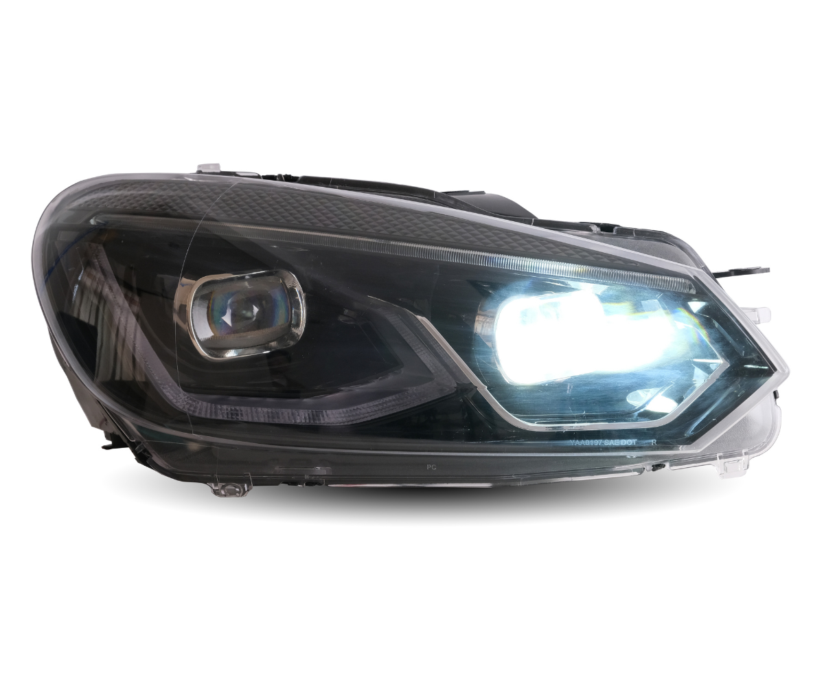 A car headlight is illuminated, emitting bright white light. The headlight features sleek, modern design lines with visible internal components, highlighted against a plain white background.