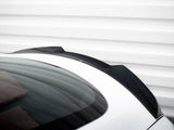 A sleek black car spoiler is mounted on a white vehicle's rear, with a reflective glass surface, set against a striped, white metal background.