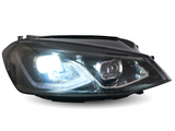A car headlight is illuminated brightly, showcasing its reflective interior design, set against a neutral, white background.