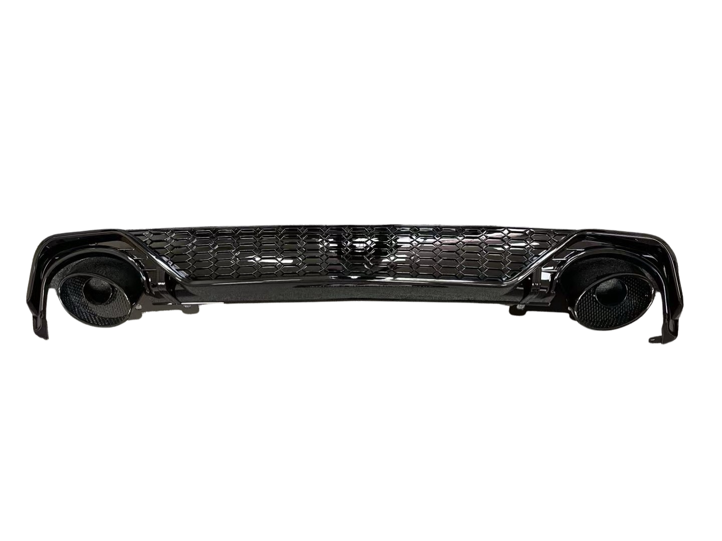 A glossy black car bumper with a honeycomb grille design, featuring circular exhaust openings on each side, isolated against a white background.