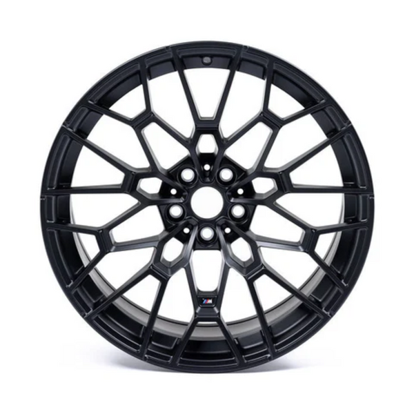 A black, intricately designed alloy wheel with a multi-spoke pattern, positioned upright on a plain white background, displaying an "M" logo near the hub.