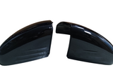 Two glossy black car side mirror covers face each other on a white background, showing smooth, curved surfaces and reflection patterns.
