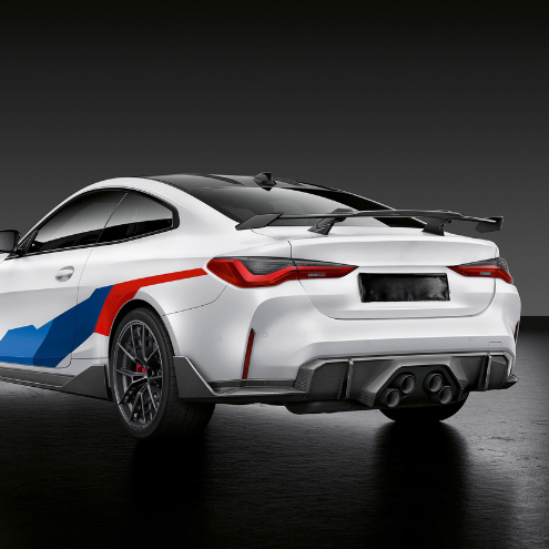 A white sports car with a large rear spoiler and colorful graphics is parked on a glossy black surface, emphasizing its sleek design and performance-oriented style.