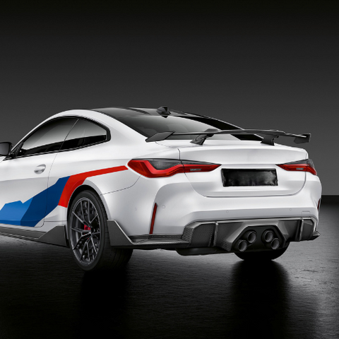 A white sports car with a large rear spoiler and colorful graphics is parked on a glossy black surface, emphasizing its sleek design and performance-oriented style.