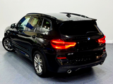 A black SUV with glowing red tail lights is stationary in a showroom, featuring 