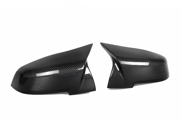 Two sleek carbon fiber side mirror covers are positioned facing each other against a plain white background. The glossy texture highlights their aerodynamic design.