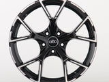 A sleek black alloy wheel with a glossy finish and five split spokes, featuring the Audi logo in the center, displayed against a plain white background.