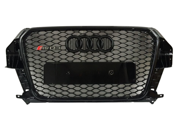 A black car grille features a honeycomb mesh design with the Audi four-ring emblem and "RS Q3" badge, set against a plain white background.