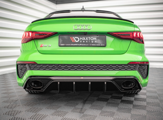 A bright green Audi RS3 is parked inside a modern garage with striped walls. The rear view highlights dual exhausts and a spoiler. The plate says "MAXTON design" with a website and phone number.