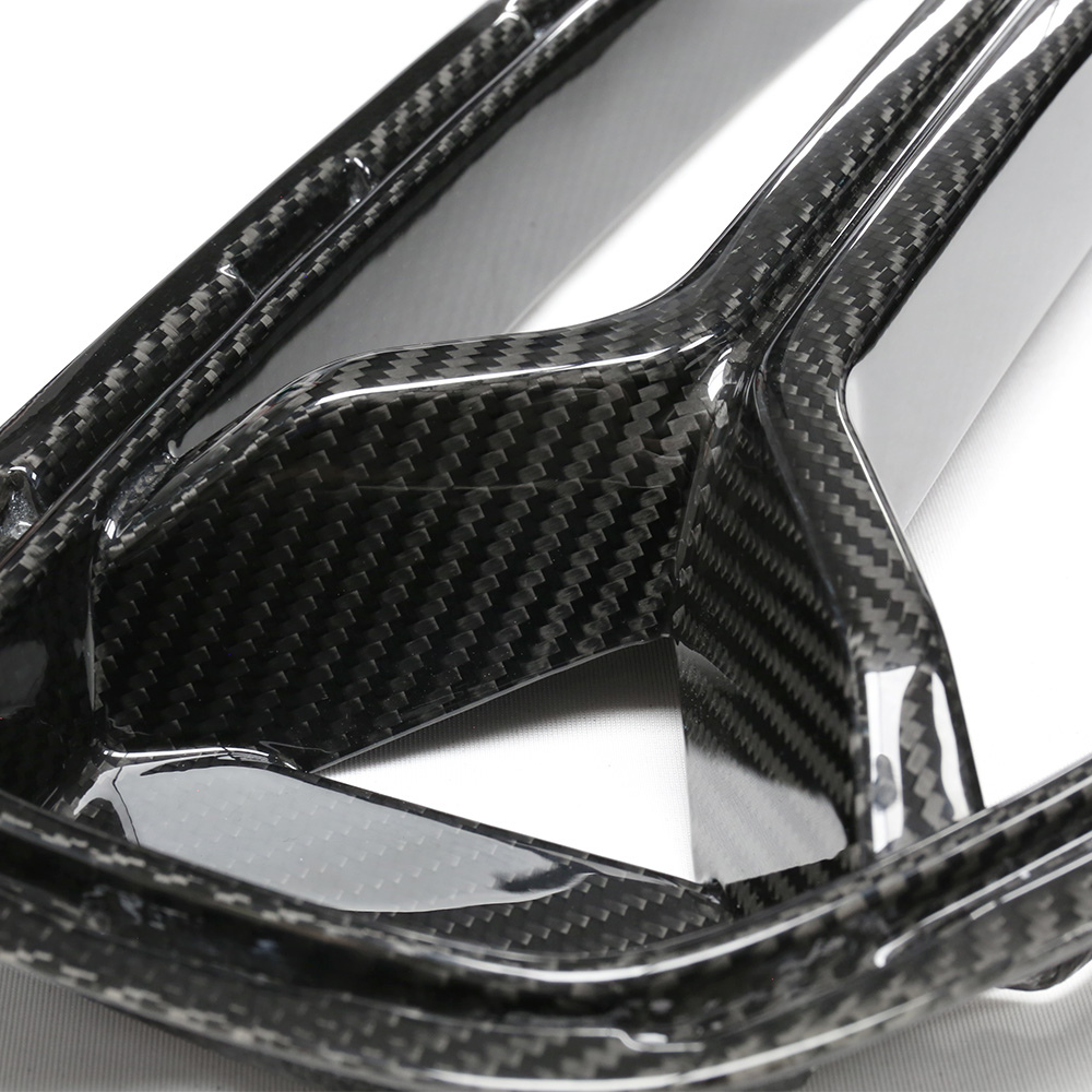 Carbon fiber panel with a glossy finish, featuring intricate weaving patterns, lies on a flat surface. It appears structured and rigid, likely part of an automotive or industrial component.