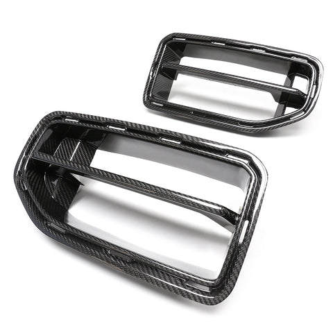 Two carbon fiber car grille inserts, one larger and one smaller, sit against a white background. The rectangular frames feature a glossy finish and prominent horizontal slats.