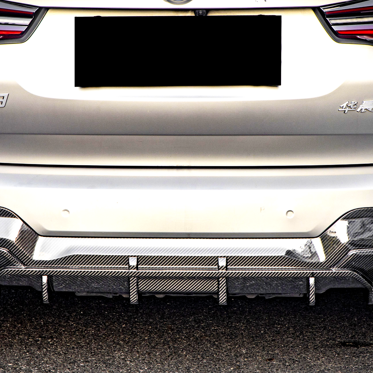 A silver car's rear with red taillights and a carbon-fiber diffuser is parked on a street. Text visible: "iX3" and Chinese characters on the back.