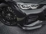 Black car with intricate alloy wheel design and sleek headlight, parked on an asphalt surface. Reflections highlight the car's glossy finish. BMW badge visible on the wheel hub.