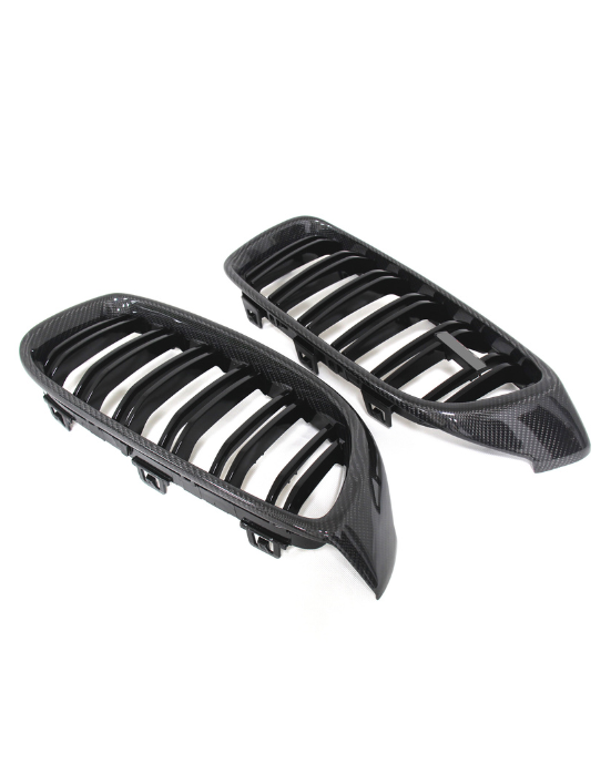 Two carbon fiber car grilles with slatted designs lying side by side on a plain white background. The grilles have shiny, textured surfaces and a sleek, aerodynamic shape.