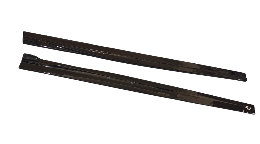 Two black, elongated, flat objects are lying parallel on a white surface, reflecting light on their glossy surfaces. They appear to be sleek, angular components possibly used in automotive or industrial applications.