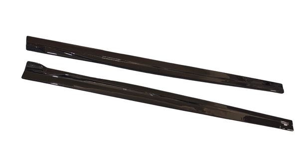 Two black, elongated, flat objects are lying parallel on a white surface, reflecting light on their glossy surfaces. They appear to be sleek, angular components possibly used in automotive or industrial applications.