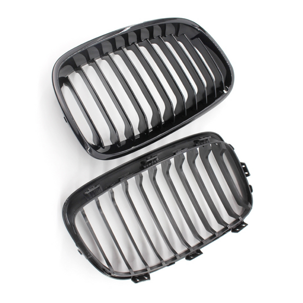 Two black, oval-shaped car grilles with vertical slats are positioned on a white background, suggesting automotive components ready for installation or inspection.