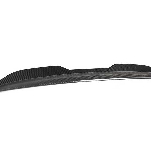 A sleek, black carbon fiber car spoiler rests against a plain white background, showcasing its aerodynamic design and smooth, modern contours.