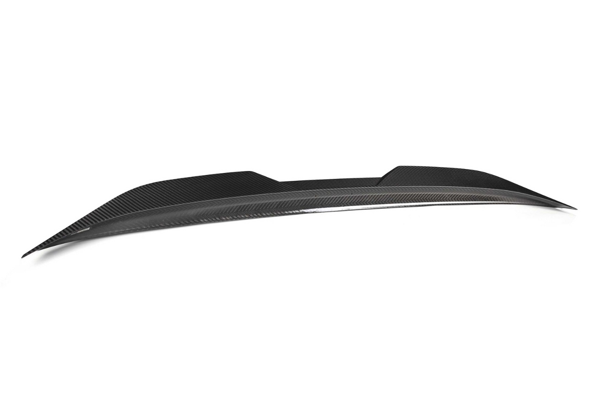 A sleek, black carbon fiber car spoiler rests against a plain white background, showcasing its aerodynamic design and smooth, modern contours.
