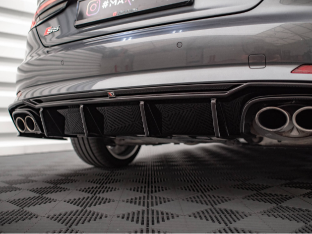 The rear of a gray car features dual exhaust pipes and a sporty diffuser. It’s parked on a patterned surface in a well-lit garage. Text: "S3," "maxhaust," "Instagram logo #MAXhaust," "YouTube logo MaxhaustTV."