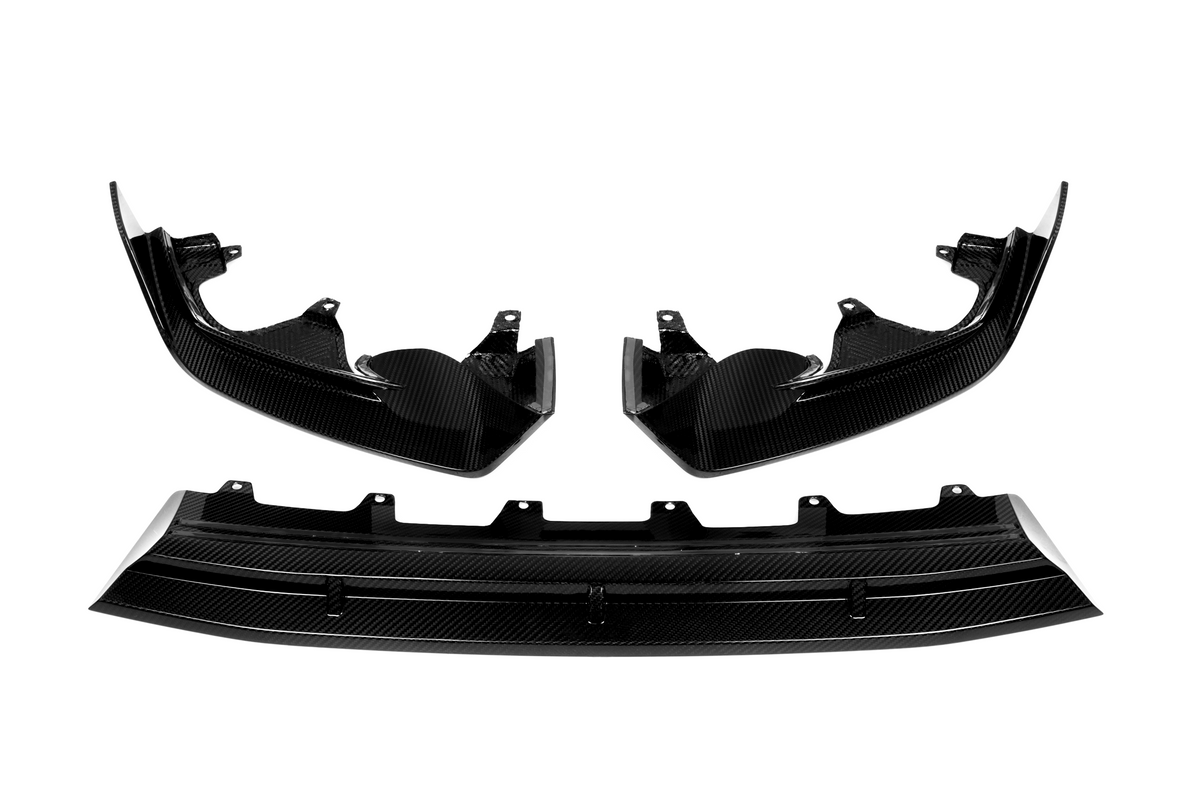 Carbon fiber car parts, including two curved side panels and a central diffuser, displayed against a white background. The pieces have a glossy finish and intricate texture.