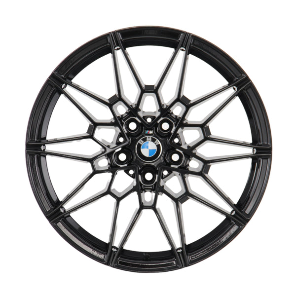 A black, intricately designed alloy wheel rim with the BMW logo at its center, viewed directly from the front, set against a plain white background.