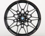 Black, intricately designed alloy wheel with a BMW logo in the center; it rests against a plain white background.