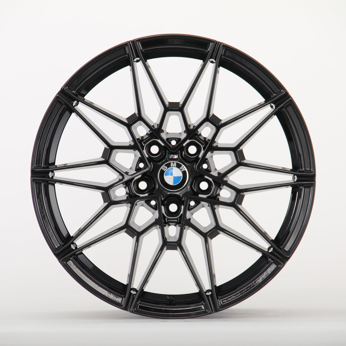Black, intricately designed alloy wheel with a BMW logo in the center; it rests against a plain white background.